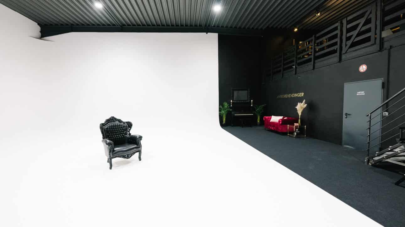 Velvet Vision Fotostudio mieten Köln Shooting Single Holzstuhl im Zimmer mit einem rosa Sofa neben der schwarzen Wand