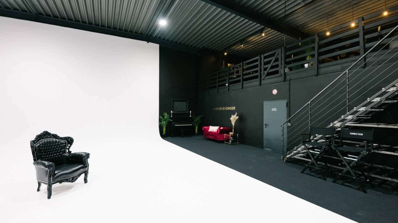 furnished area with a pink colored sofa by the black wall and a room door shot at miet fotostudio