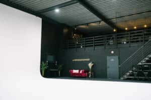 eingerichteter Bereich mit einem rosafarbenen Sofa an der schwarzen Wand und einer Zimmertür geschossen bei miet fotostudio
