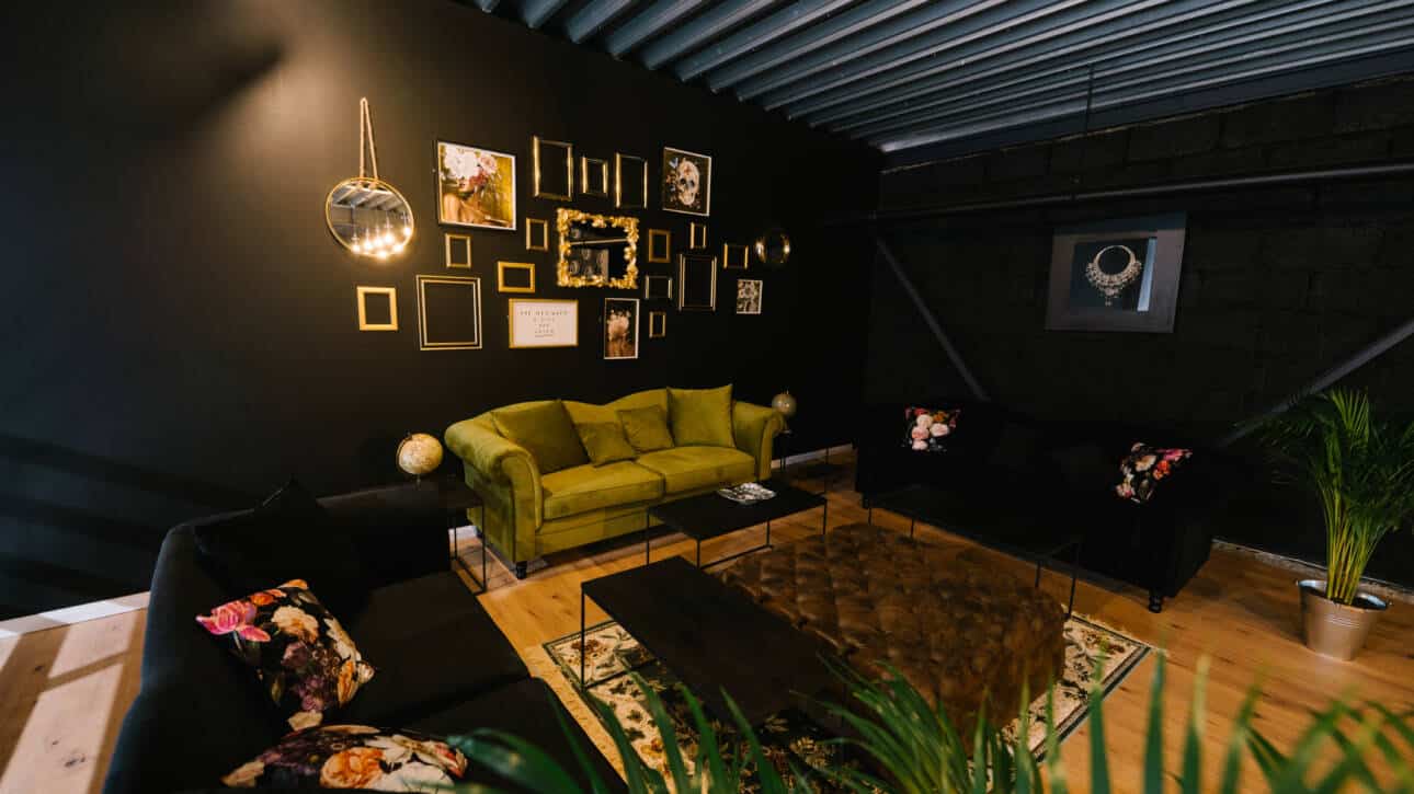 Salon mit grünem Sofa an der schwarzen Wand und ein Tisch in der Mitte des Velvet Vision Studios mieten Köln