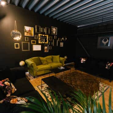 Salon mit grünem Sofa an der schwarzen Wand und ein Tisch in der Mitte des Velvet Vision Studios mieten Köln