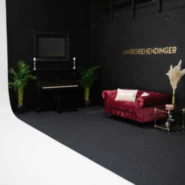 eingerichteter Bereich mit einem rosafarbenen Sofa an der schwarzen Wand geschossen bei miet fotostudio